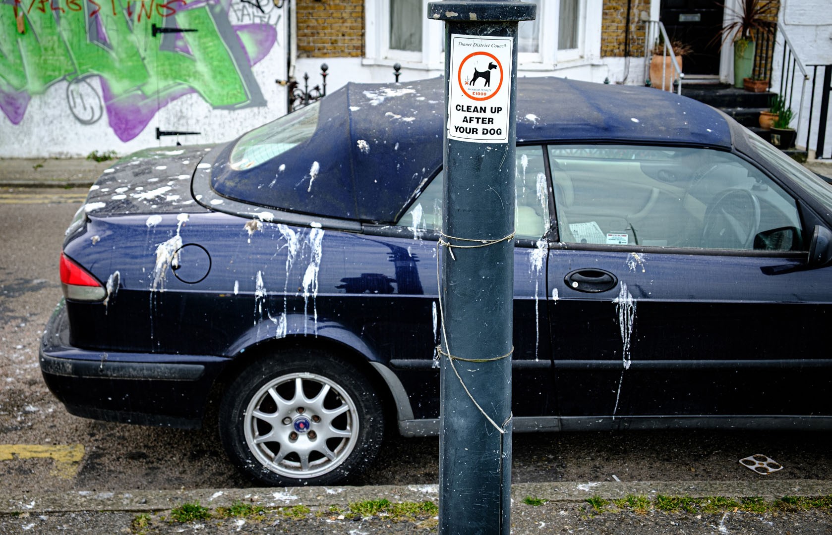 Street photograph by Russ Pullen — a car parked beside a clean-up-after-your-dog sign in Thanet, Kent
